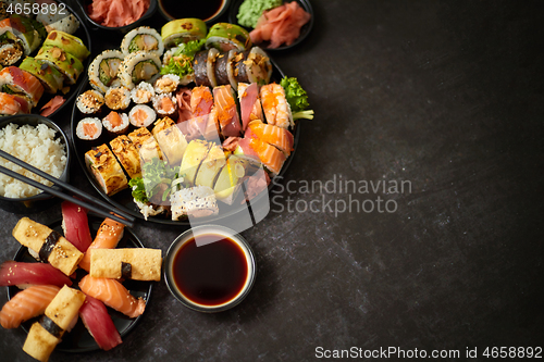 Image of Assorted sushi set served on dark dark background. Top view of seafood, various maki rolls