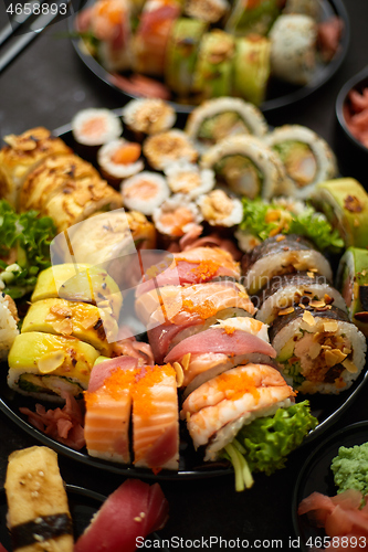 Image of Assorted sushi set served on dark dark background. Top view of seafood, various maki rolls