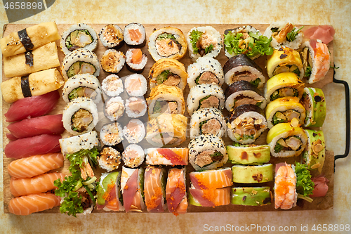 Image of Above view of various sushi and rolls placed on wooden board. Japanese food fest