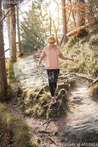 Image of Active sporty woman running in autumn fall forest jumping over the roots on the path. Healthy lifestyle image of young active caucasian woman jogging outside in nature