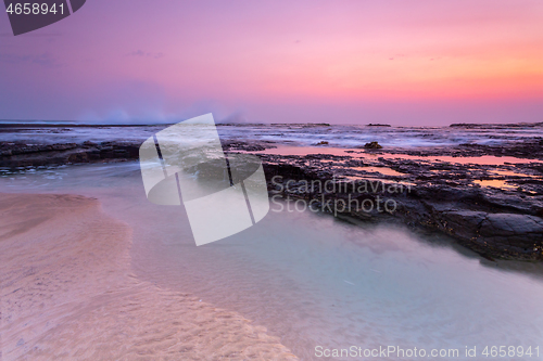 Image of Pretty sunrise over the beach and rock shelf with reflections