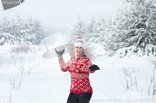 Image of Happy woman throwing a large snowball in winter