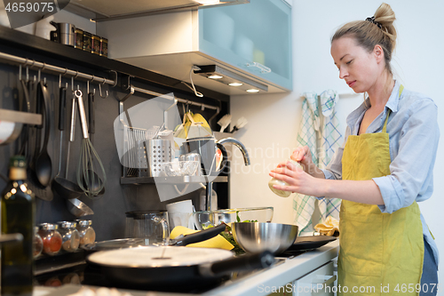 Image of Stay at home housewife woman cooking in kitchen, stir frying dish in a saucepan, preparing food for family dinner.