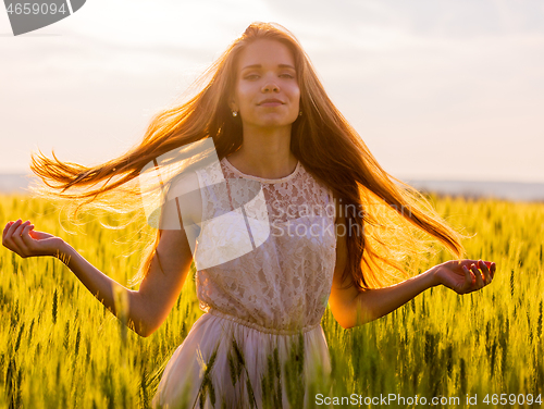 Image of Girl with flowing hair backlit by sunset