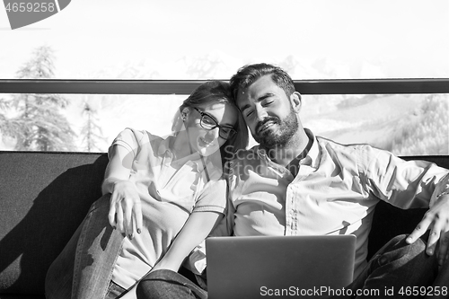 Image of couple relaxing at  home using laptop computers