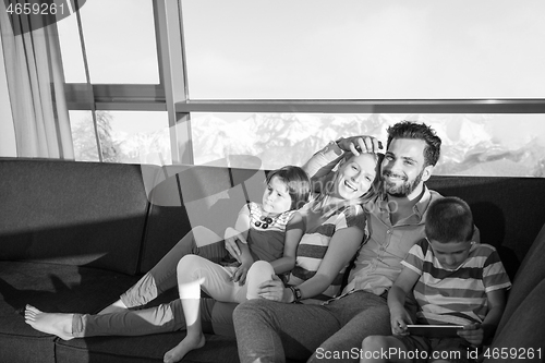 Image of happy young couple spending time with kids at home