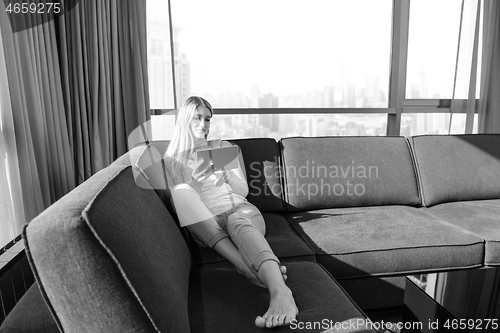 Image of young woman on sofa at home surfing web