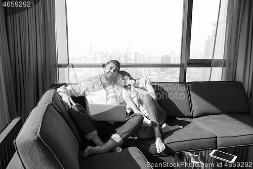 Image of couple relaxing at  home using laptop computers