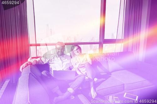 Image of couple relaxing at  home using laptop computers