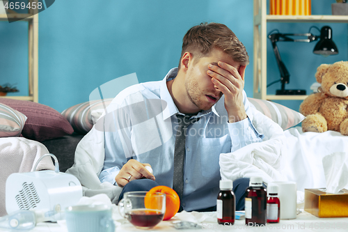 Image of Bearded sick man with flue sitting on sofa at home. Illness, influenza, pain concept. Relaxation at Home. Healthcare Concepts.