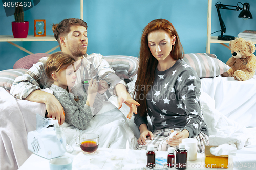 Image of The young parents with sick daughter at home. The ill family.