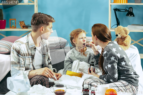 Image of The young parents with sick daughter at home. The ill family.