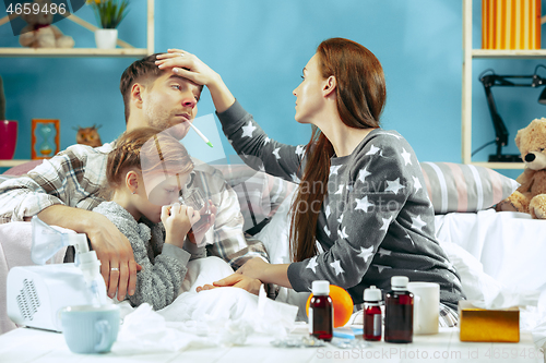 Image of The young parents with sick daughter at home. The ill family.