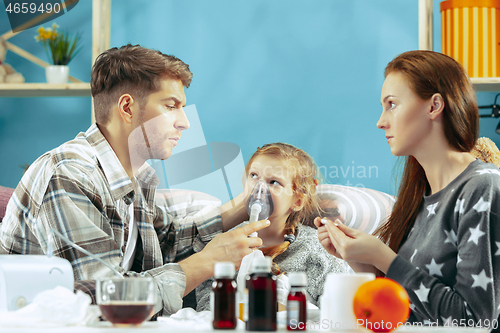 Image of The young parents with sick daughter at home. The ill family.