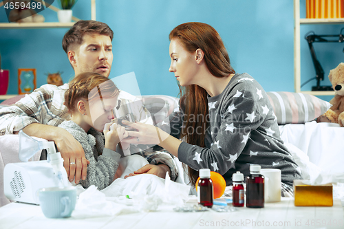 Image of The young parents with sick daughter at home. The ill family.