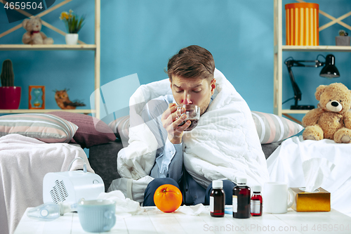 Image of Bearded sick man with flue sitting on sofa at home. Illness, influenza, pain concept. Relaxation at Home. Healthcare Concepts.