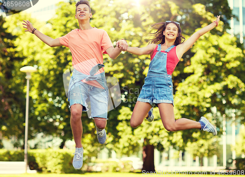 Image of happy teenage couple jumping at summer park