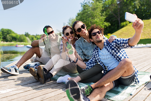 Image of friends with drinks taking selfie by smartphone