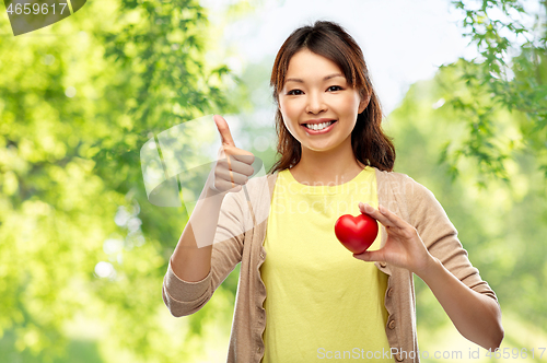 Image of happy asian woman with red heart showing thumbs up