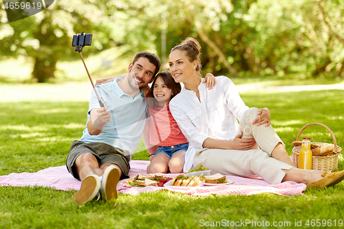 Image of family having picnic and taking selfie at park