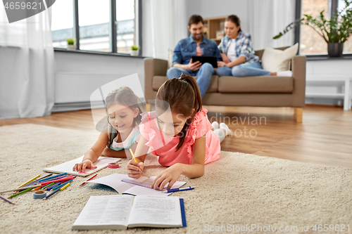 Image of happy sisters drawing and doing homework at home