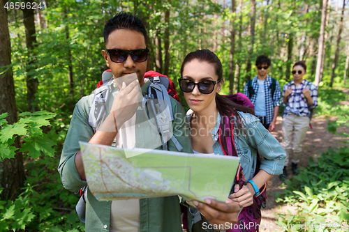 Image of friends with map and backpacks hiking in forest