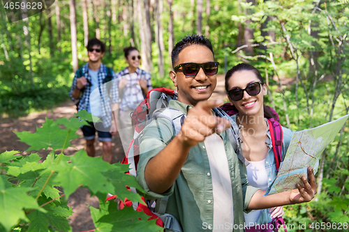 Image of friends with map and backpacks hiking in forest