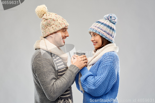 Image of happy couple in winter clothes holding one cup