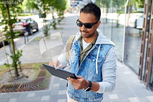 Image of man with tablet pc and backpack on city street