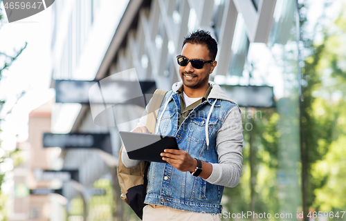 Image of man with tablet pc and backpack on city street
