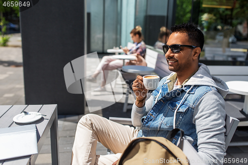 Image of indian man drinking coffee at city street cafe