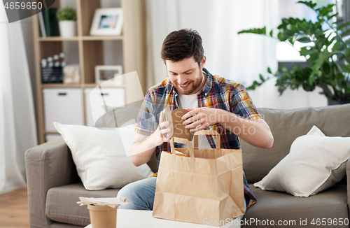 Image of smiling man unpacking takeaway food at home