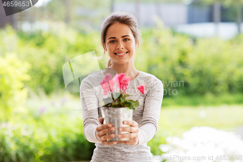 Image of young woman with cyclamen flowers at summer garden