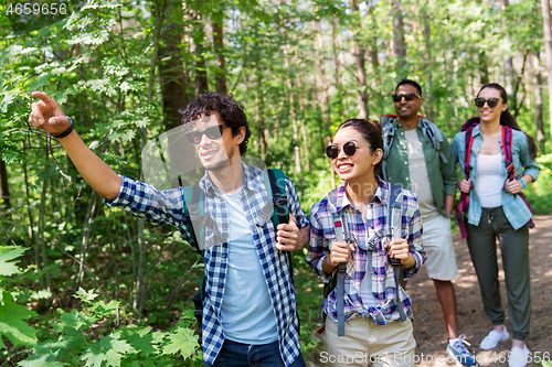 Image of group of friends with backpacks hiking in forest