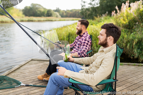 Image of male friends fishing and drinking beer on lake