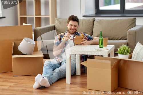 Image of smiling man eating takeaway food at new home