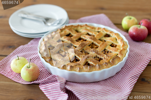 Image of apple pie in baking mold on wooden table