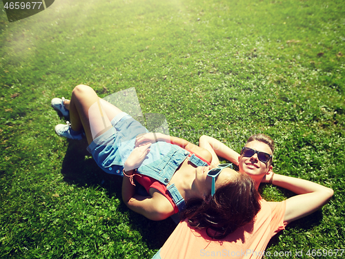 Image of happy teenage couple lying on grass at summer