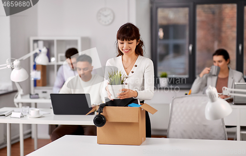 Image of happy employee with personal stuff at office