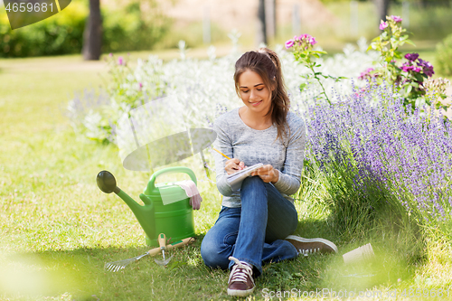 Image of young woman writing to notebook at summer garden