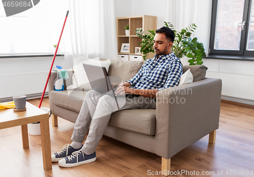 Image of man with laptop computer after home cleaning