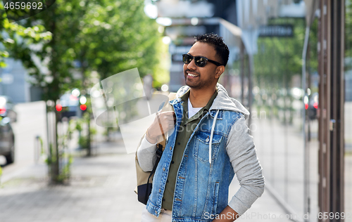 Image of indian man in sunglasses with backpack in city