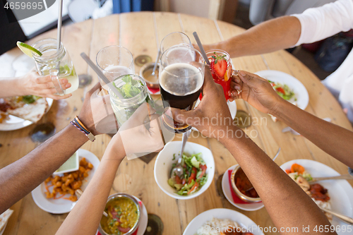 Image of friends eating and clinking glasses at restaurant