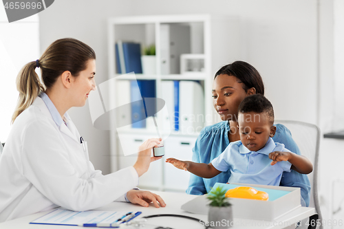 Image of doctor giving medicine to woman with son at clinic