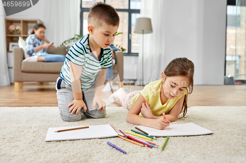 Image of brother and sister drawing with crayons at home