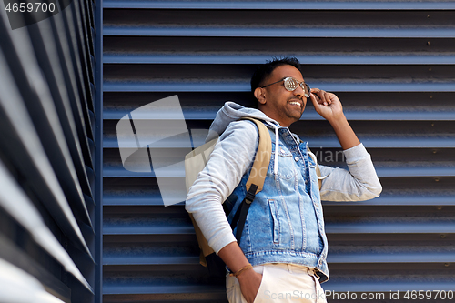 Image of smiling indian man with backpack on city street