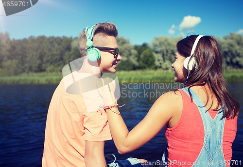 Image of teenage couple with headphones on river berth