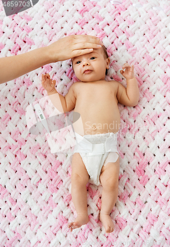 Image of mother\'s hand measuring temperature of baby girl