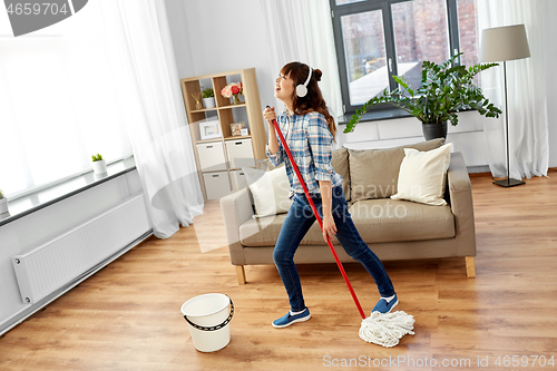 Image of asian woman or housewife with mop singing at home
