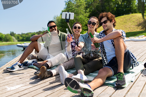 Image of friends with drinks taking selfie on lake pier